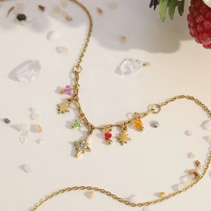 Gold necklace with colorful charms on a light background